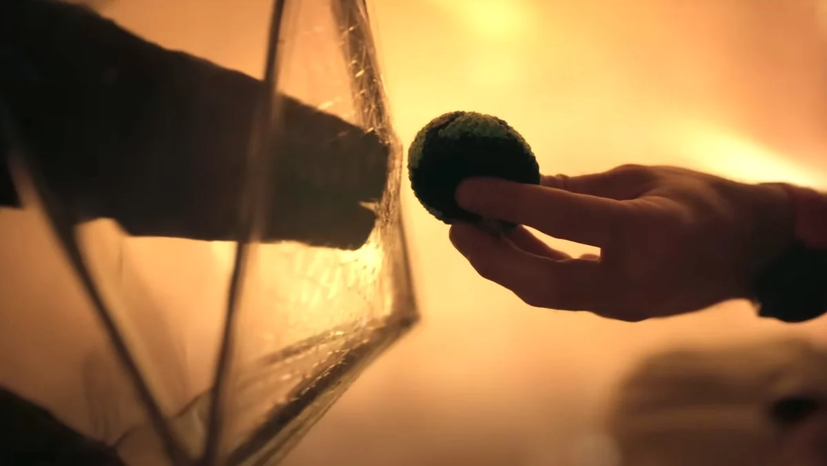 Rocky's hand reaches out to Grace's between a prismatic shield.